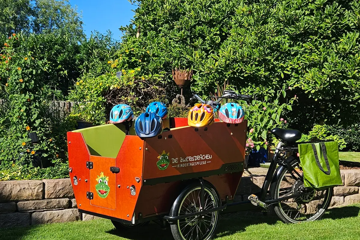 Lastenrad im Garten mit Helmen für Ausflüge in der Kindertagespflege
